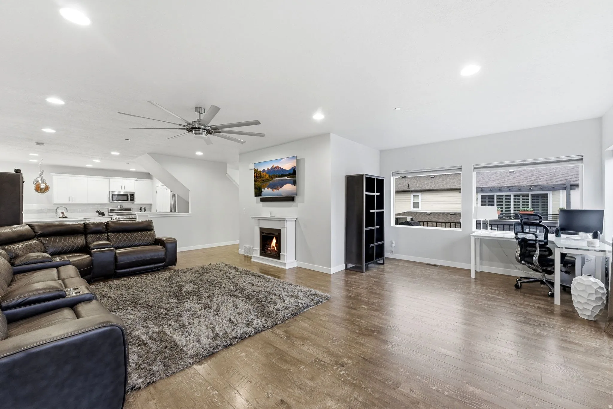 Living area featuring an office area, a lit fireplace, dark wood-style flooring, a ceiling fan, and recessed lighting