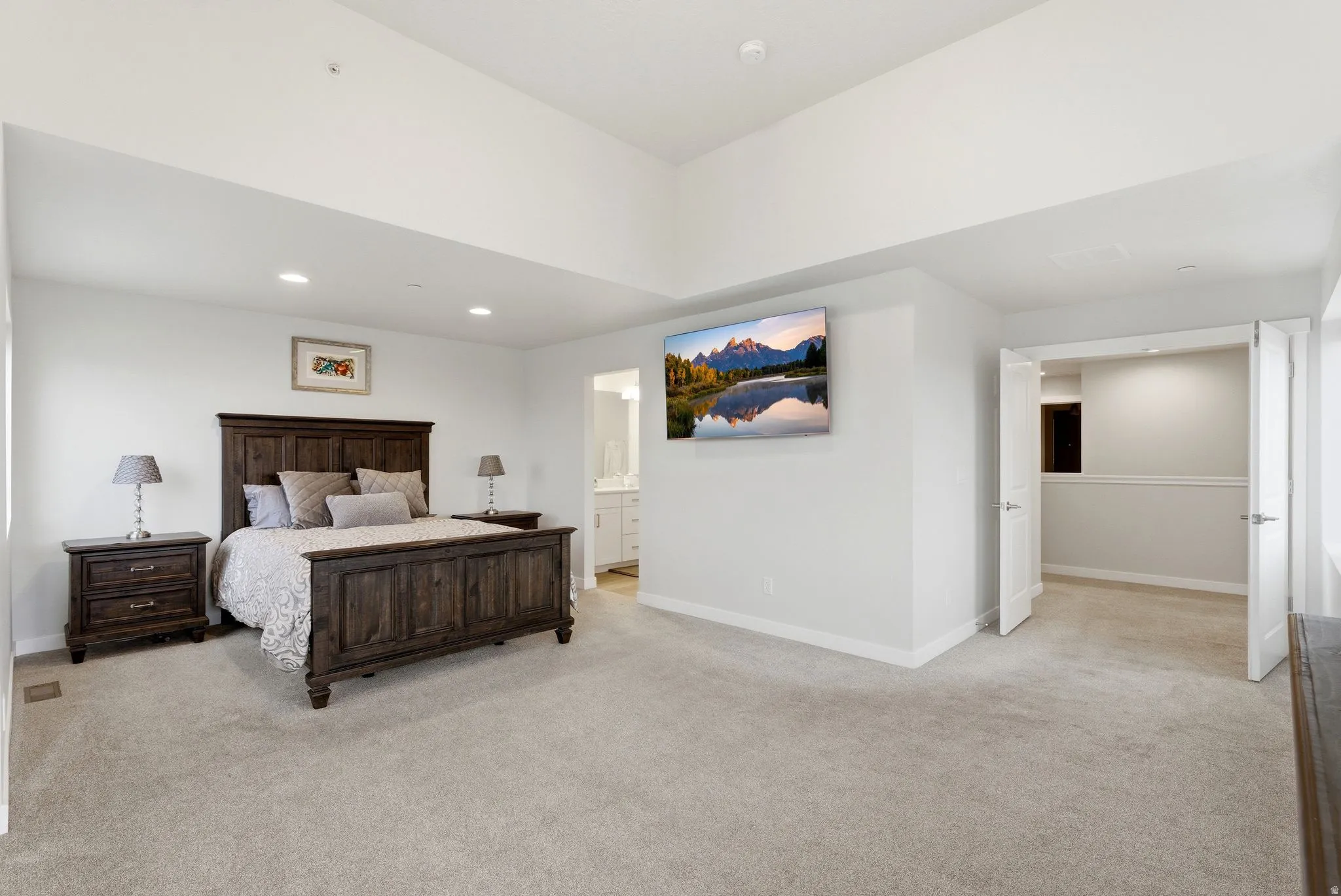 Bedroom featuring light colored carpet, recessed lighting, and ensuite bath
