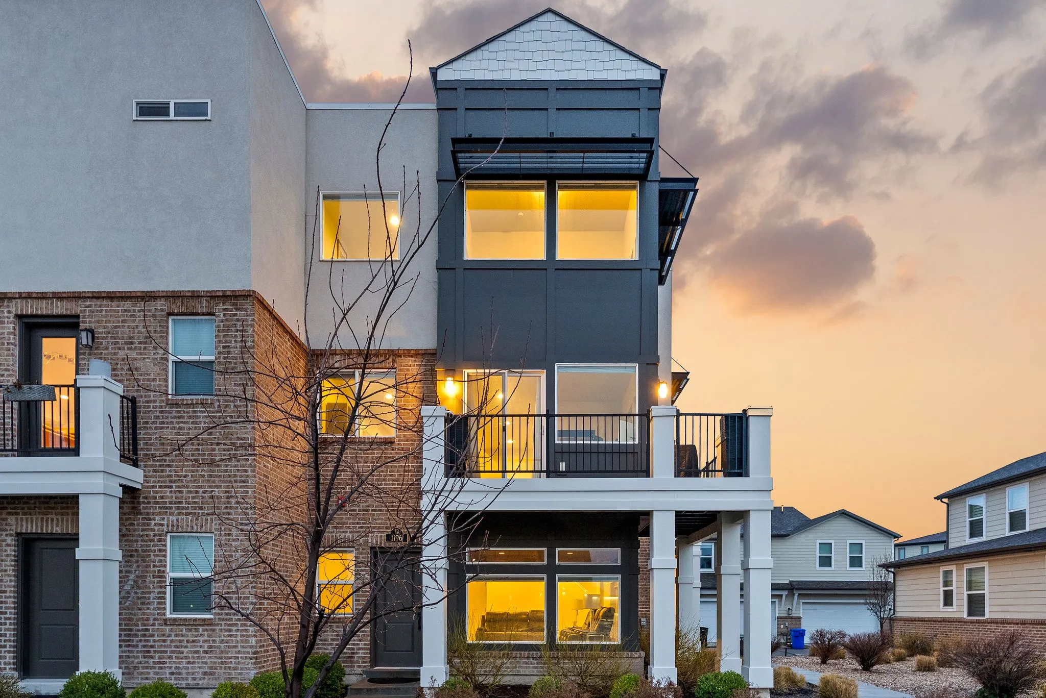 Contemporary house with a balcony, brick siding, and stucco siding