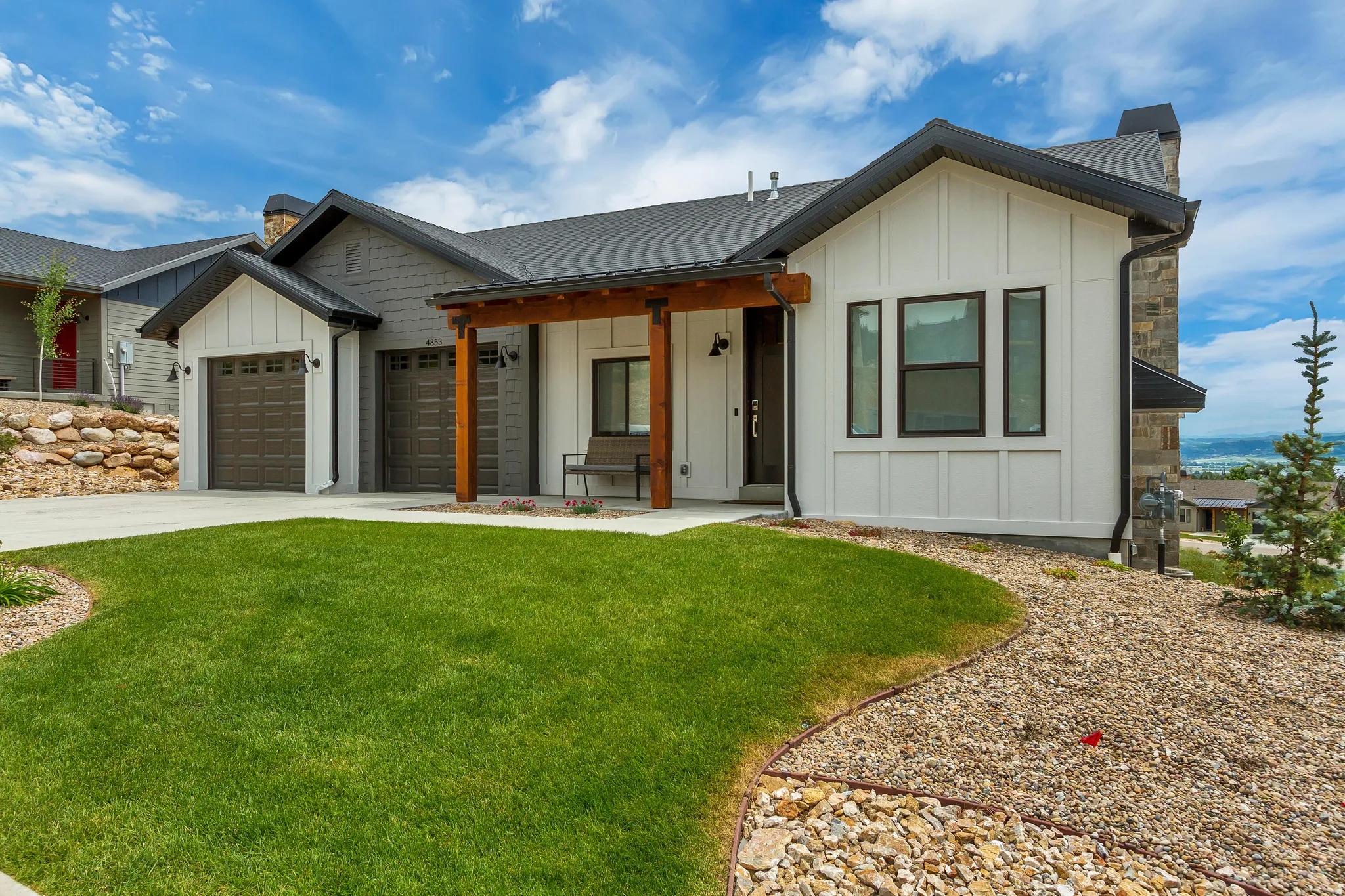Modern farmhouse style home with board and batten siding, a front yard, driveway, and a chimney