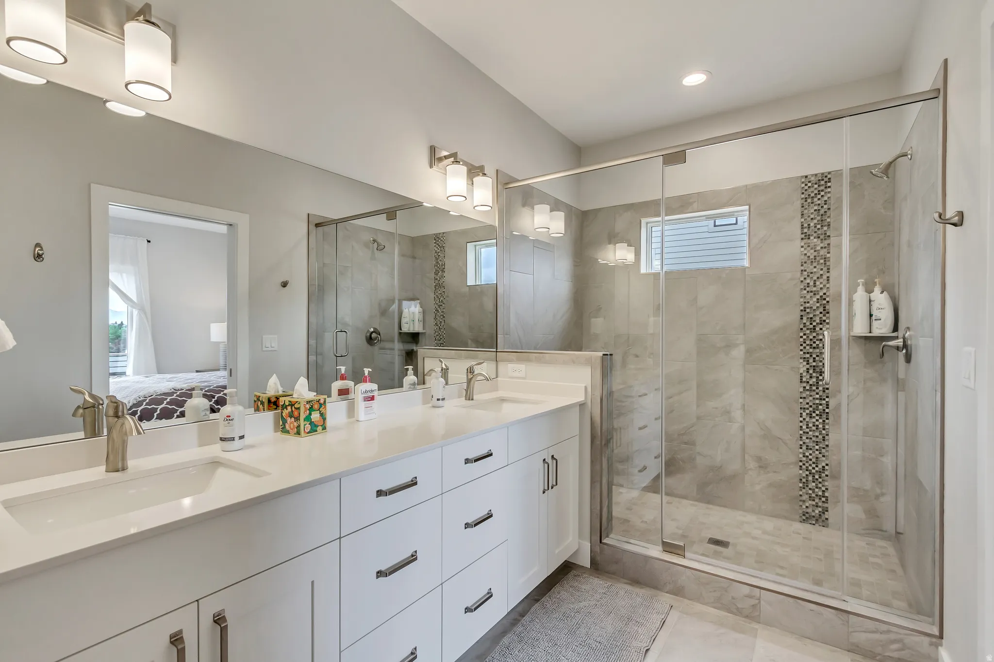 Full bathroom with connected bathroom, double vanity, and a stall shower