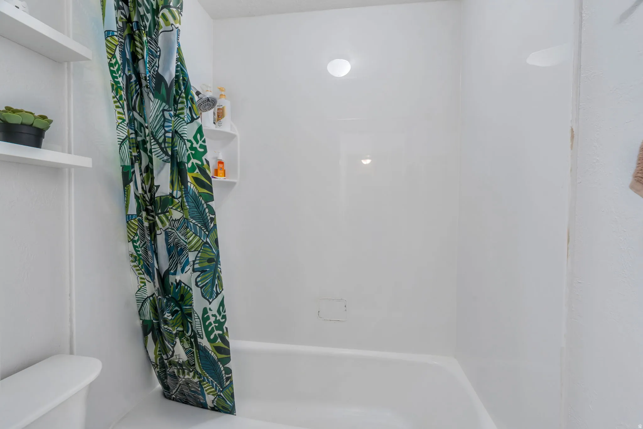 Bathroom featuring toilet and shower / bath combination with curtain