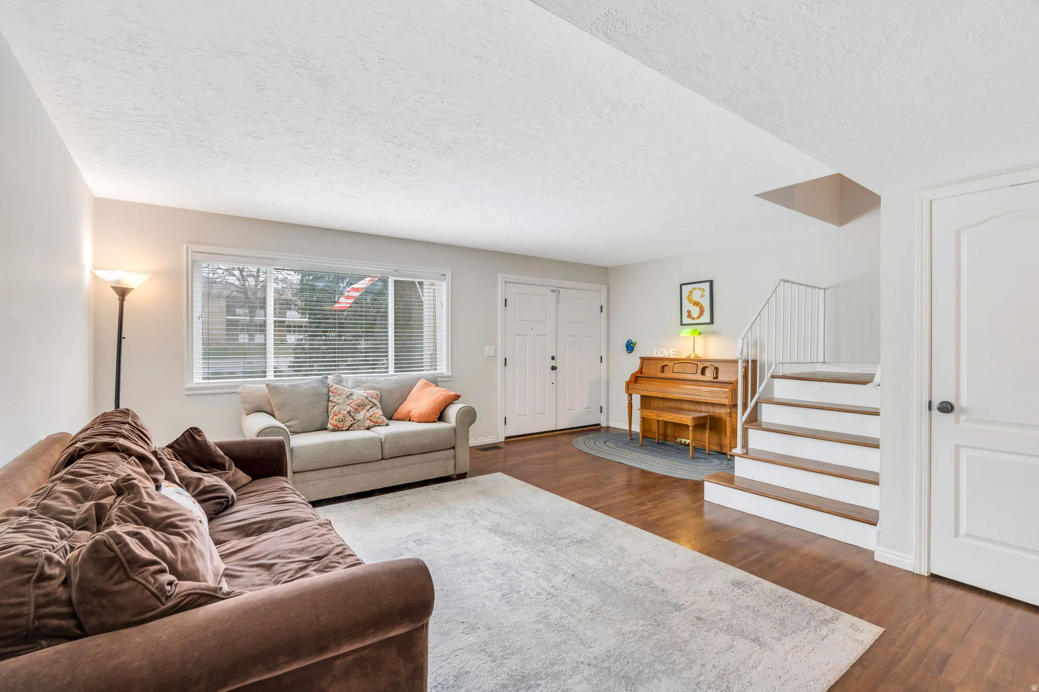 Living area with a textured ceiling and dark wood-type flooring