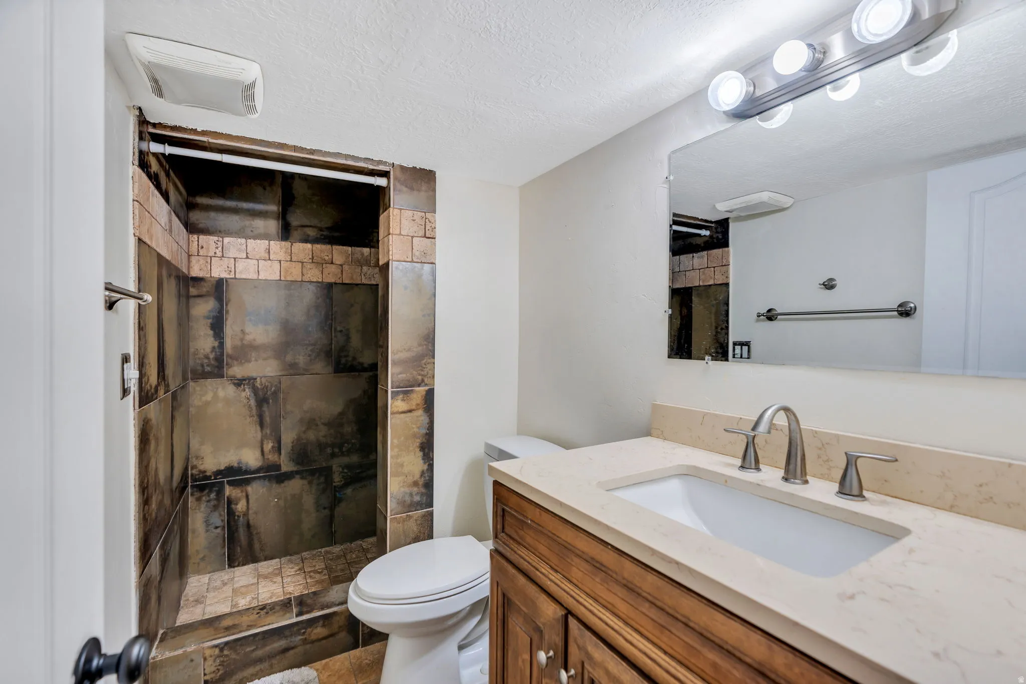 Bathroom featuring a shower stall, vanity, and a textured ceiling