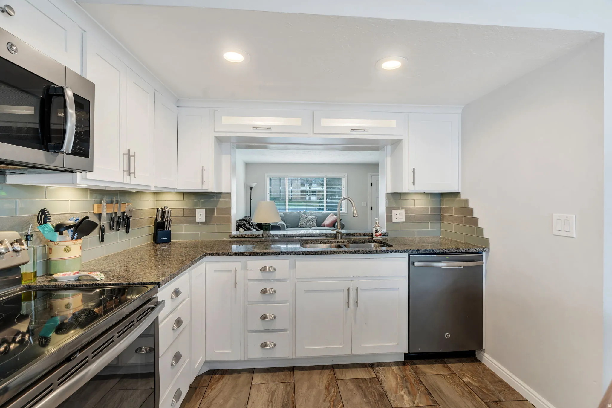 Kitchen featuring stainless steel appliances, dark stone counters, white cabinetry, tasteful backsplash, and recessed lighting