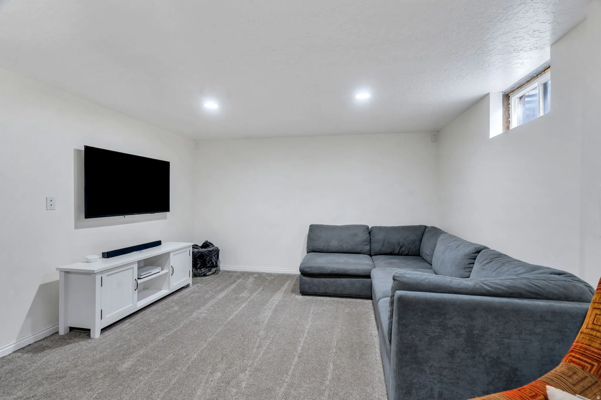 Living area with light carpet and recessed lighting