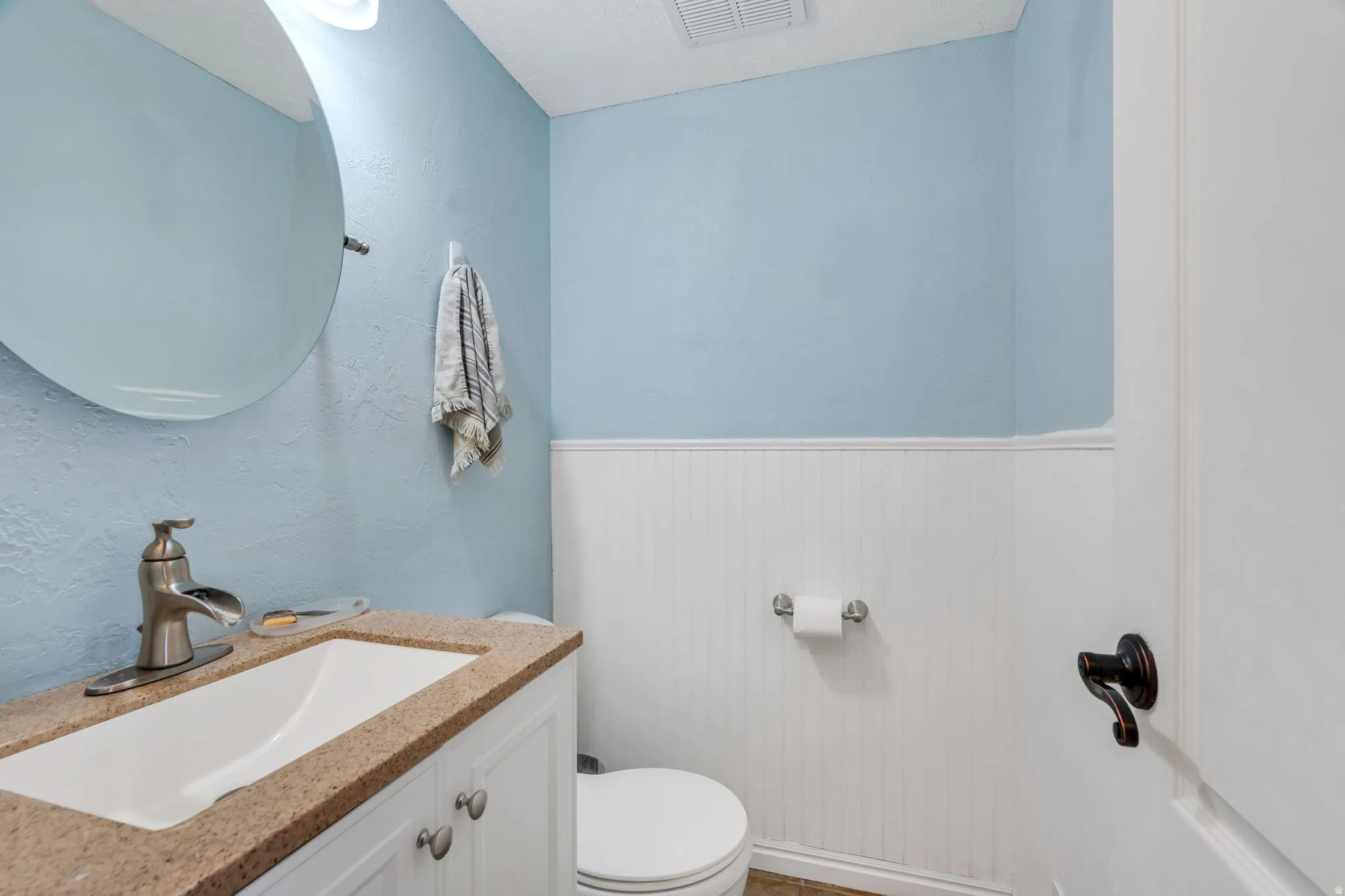 Bathroom with vanity, a wainscoted wall, and wood walls
