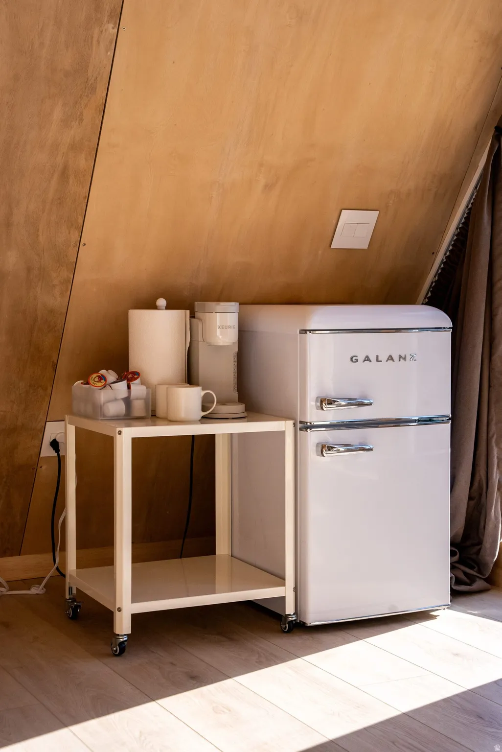 Detailed view of light wood finished floors and freestanding refrigerator