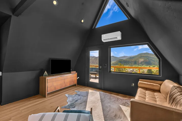 Cinema room with lofted ceiling, light wood-style floors, and a mini split for heating / cooling