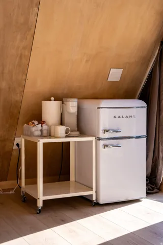 Detailed view of light wood finished floors and freestanding refrigerator