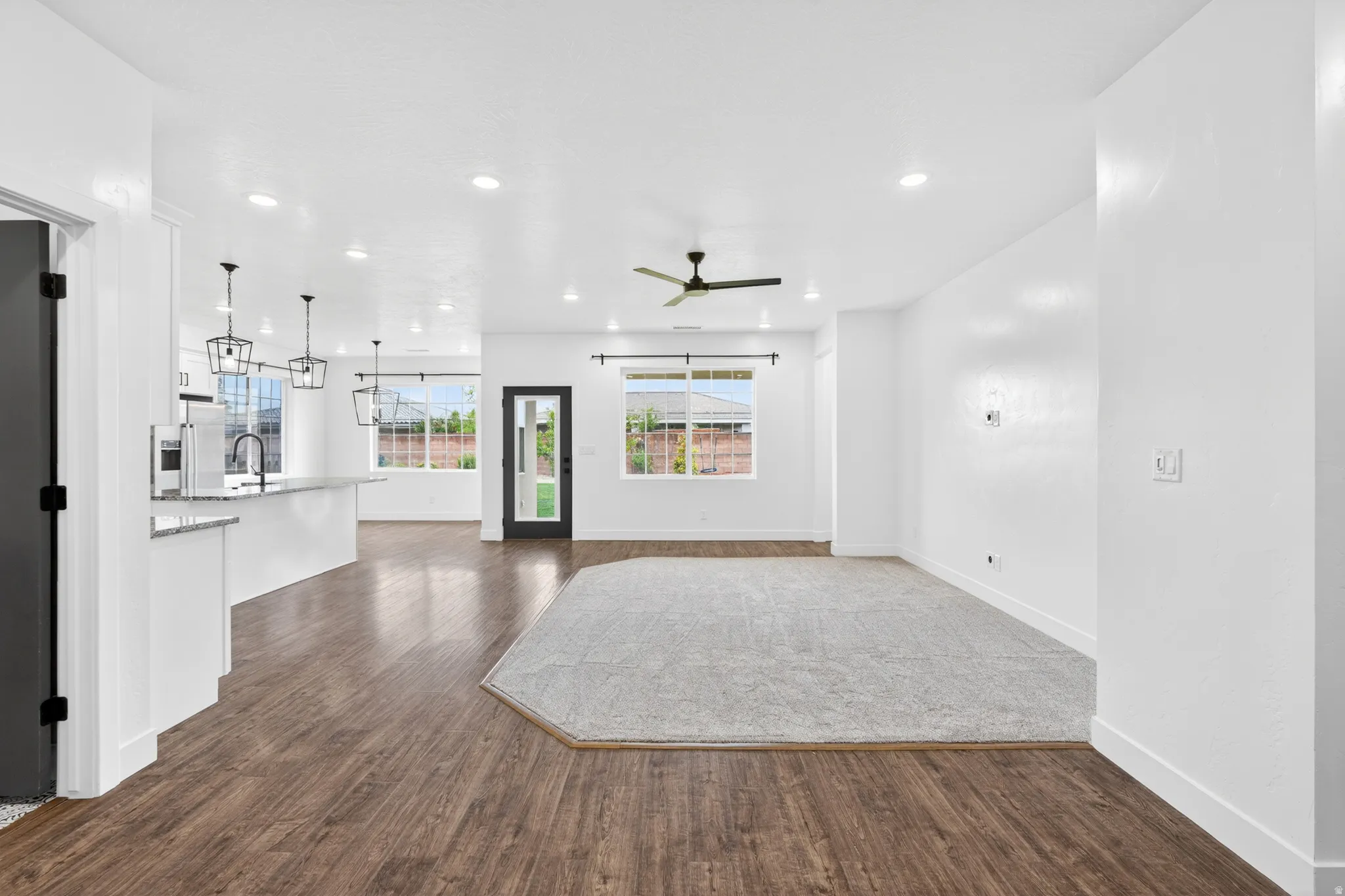 Unfurnished living room with dark wood-style floors, ceiling fan, and recessed lighting