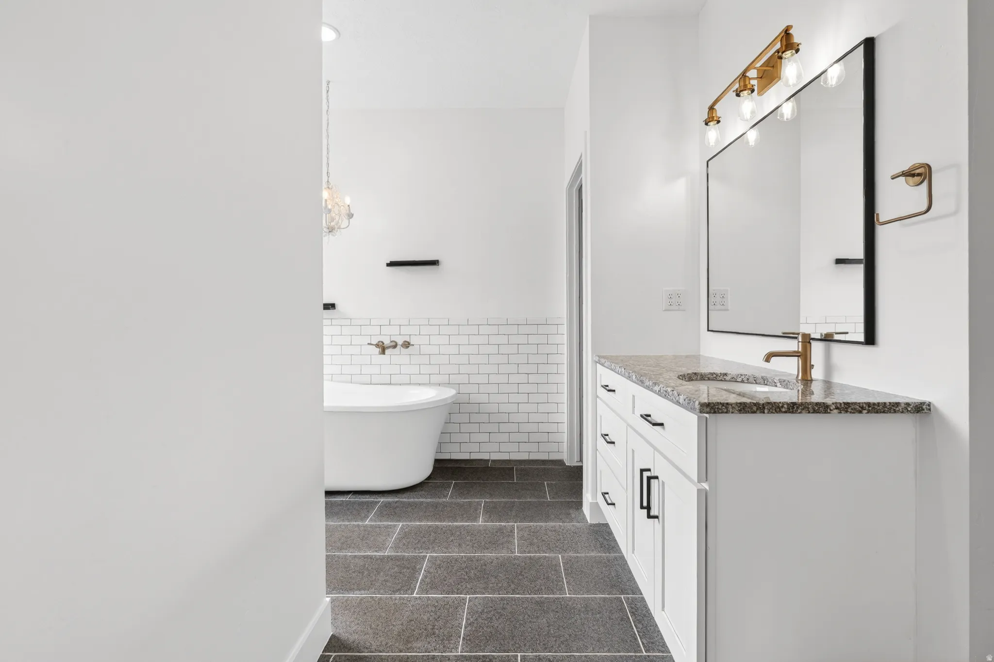 Bathroom with vanity, tile walls, a freestanding bath, and wainscoting