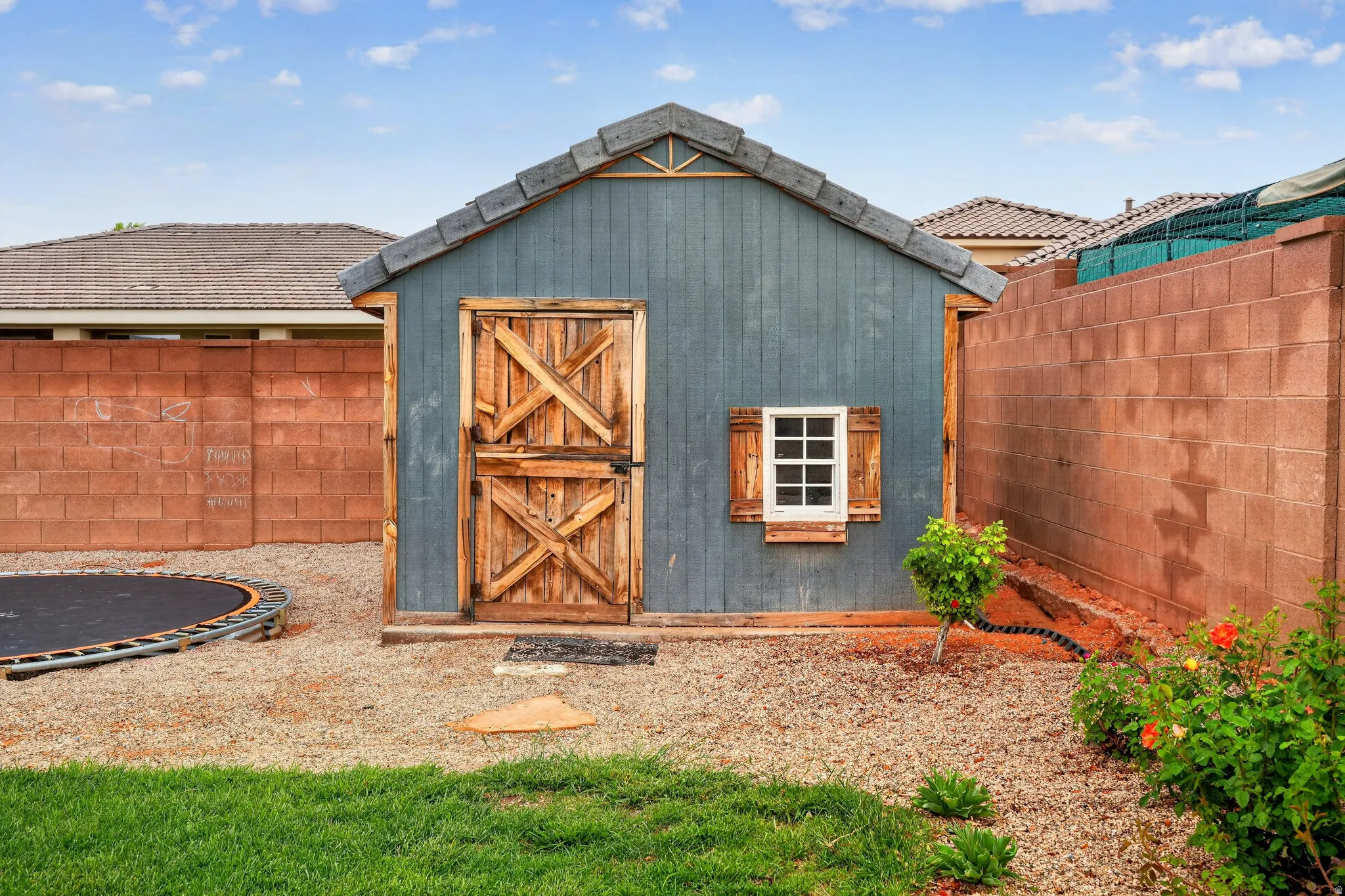 View of shed/playhouse with a fenced backyard and a trampoline, has power