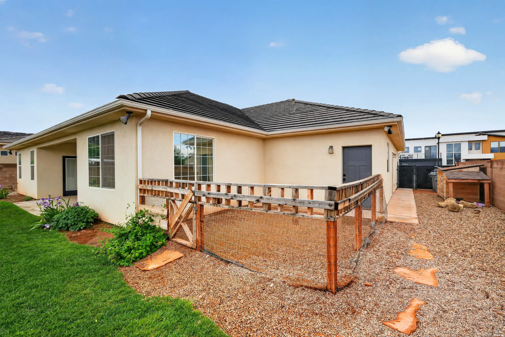View of property exterior featuring stucco siding and a fenced dog run and backyard