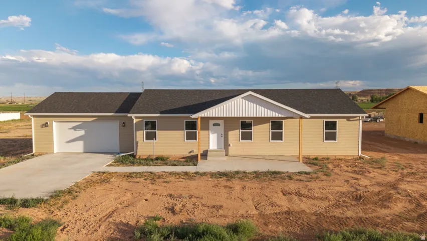 Ranch-style residence featuring a prominent two-car garage, light beige siding, and a contrasting dark shingle roof