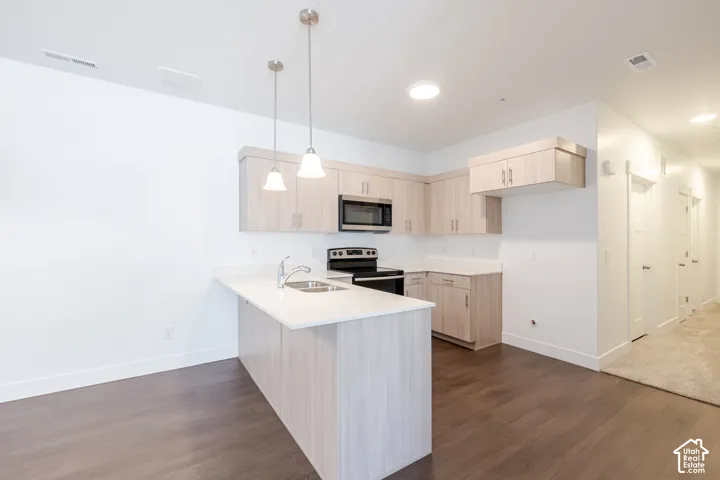 Kitchen featuring wood-finish cabinetry, stainless steel microwave, and pendant lighting