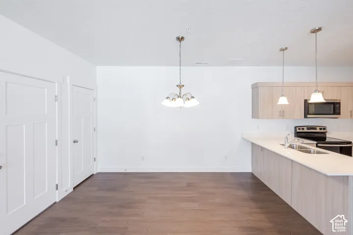 Wood-finish flooring throughout, with a contemporary kitchen featuring light-toned cabinetry, a stainless steel sink, and pendant lighting