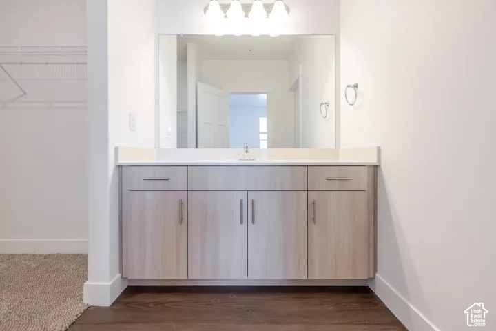 Vanity with light wood-finish cabinetry, white countertop, and integrated sink