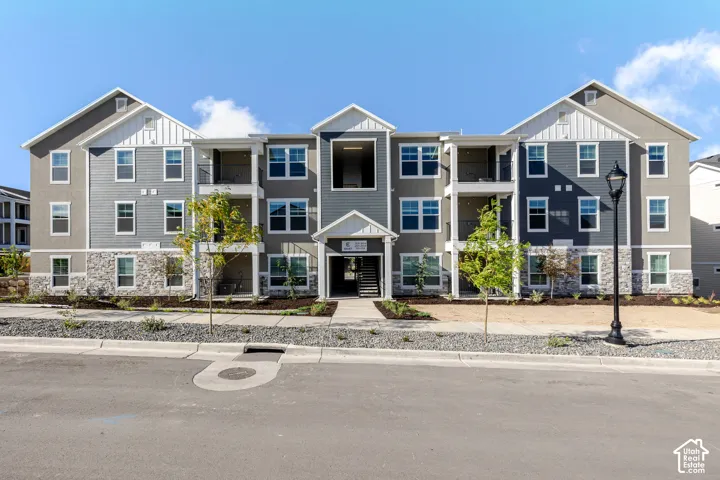 Multi-story building featuring gray horizontal siding, white vertical siding accents, and a stone facade