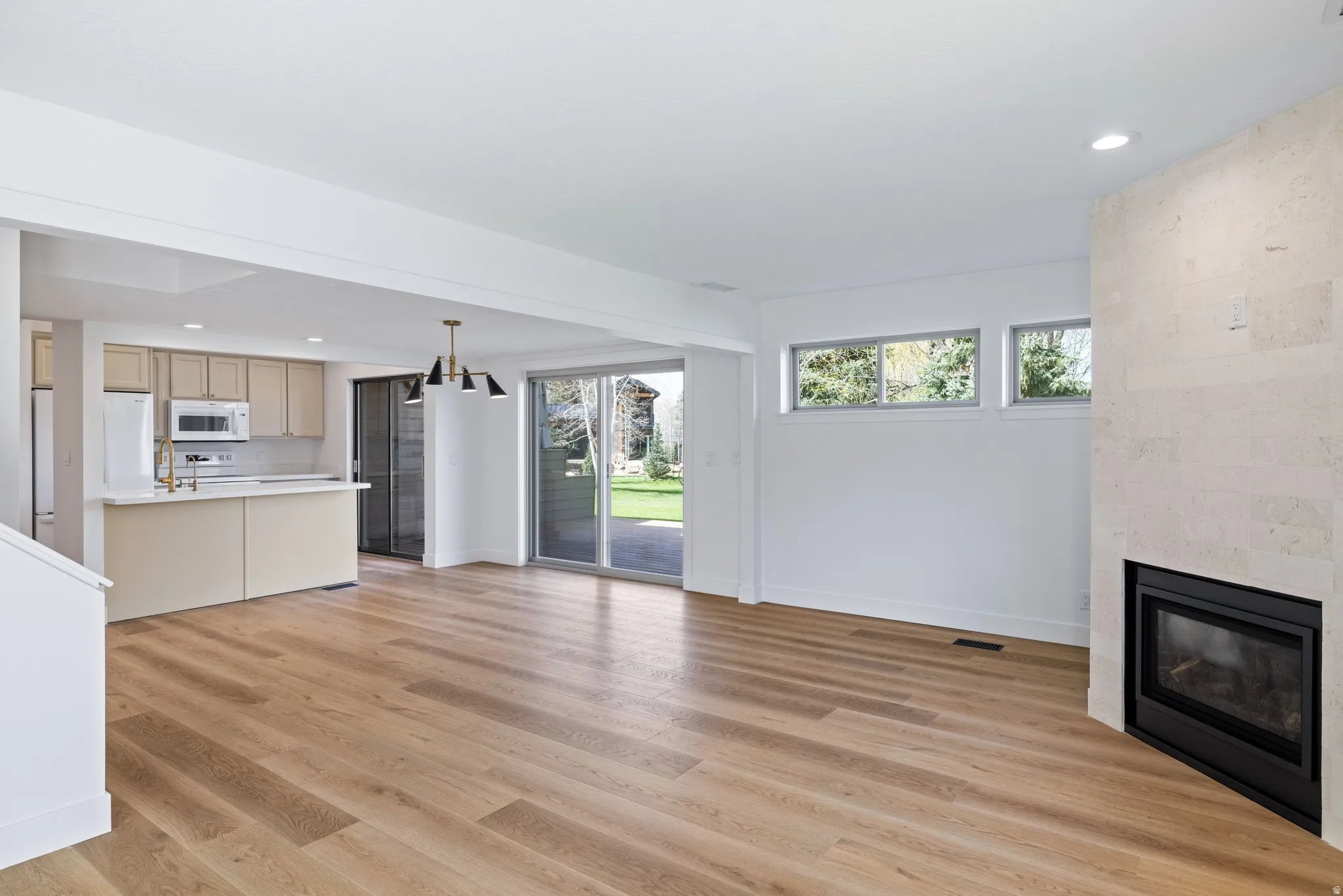 Unfurnished living room with a large fireplace, light wood-type flooring, and hanging lights