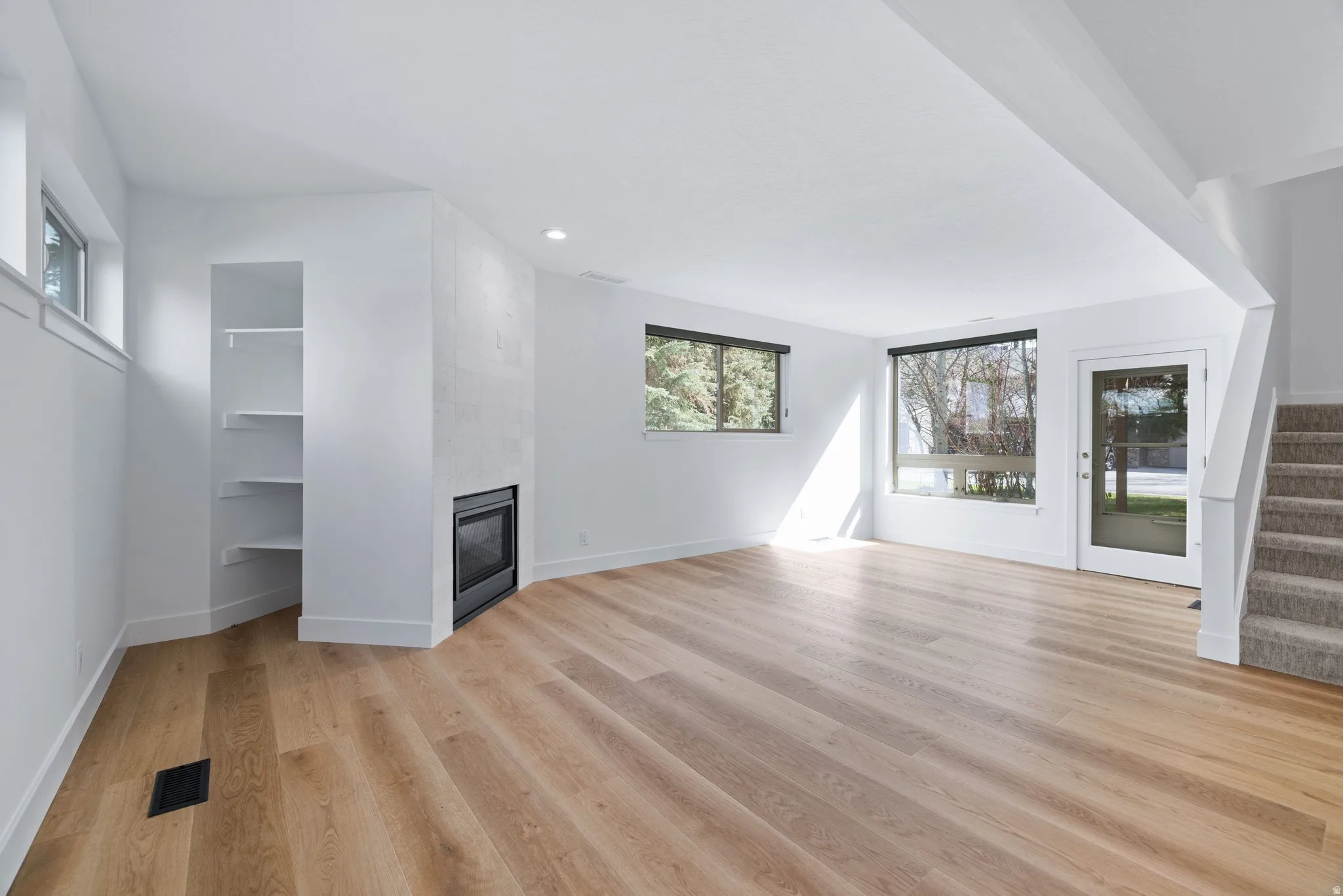 Unfurnished living room featuring a tile fireplace, light wood-style flooring, and recessed lighting