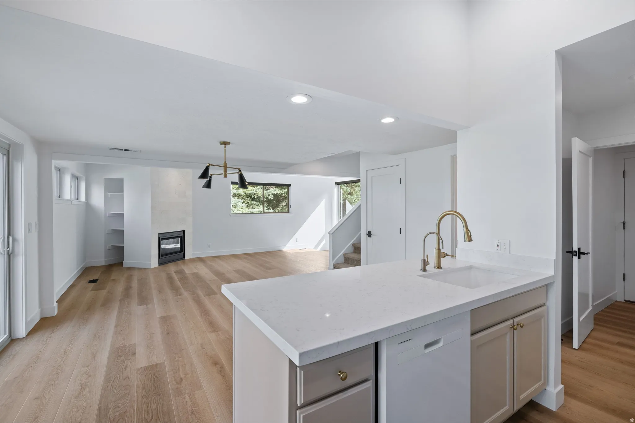 Kitchen with white dishwasher, a fireplace, light wood-style floors, recessed lighting, and open floor plan