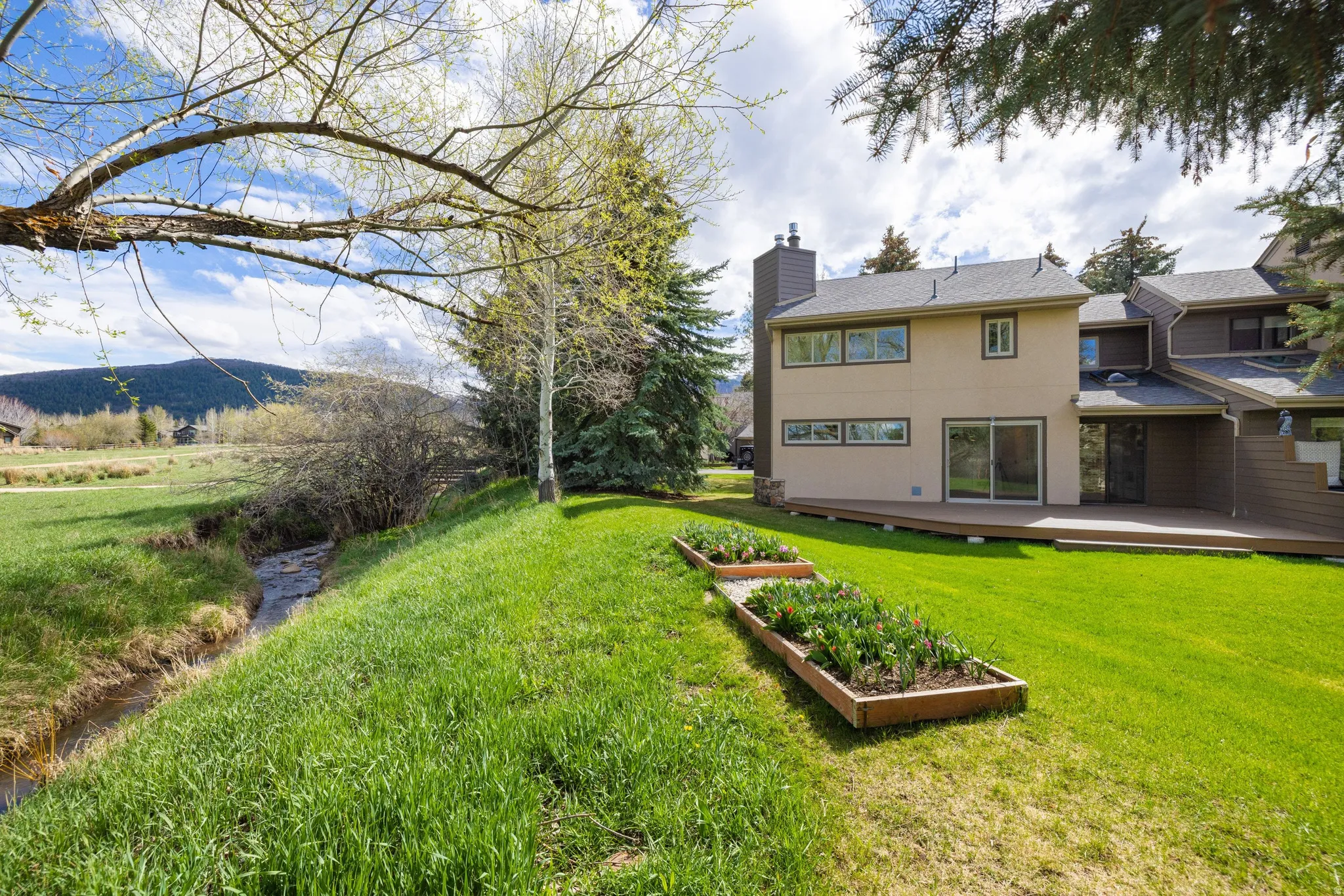 Rear view of property with a lawn, a chimney, and a garden