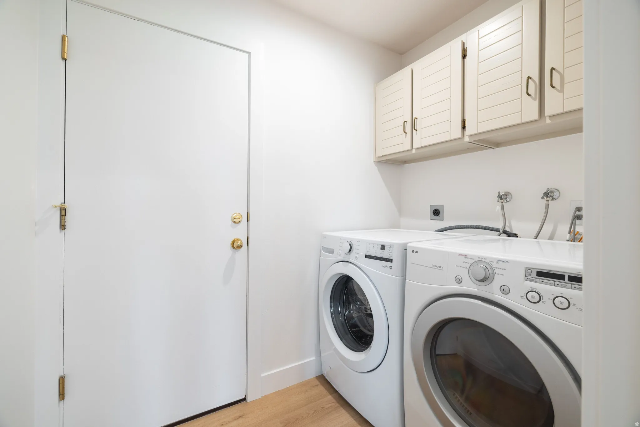 Laundry room featuring cabinet space, light wood-style flooring, and washer and dryer