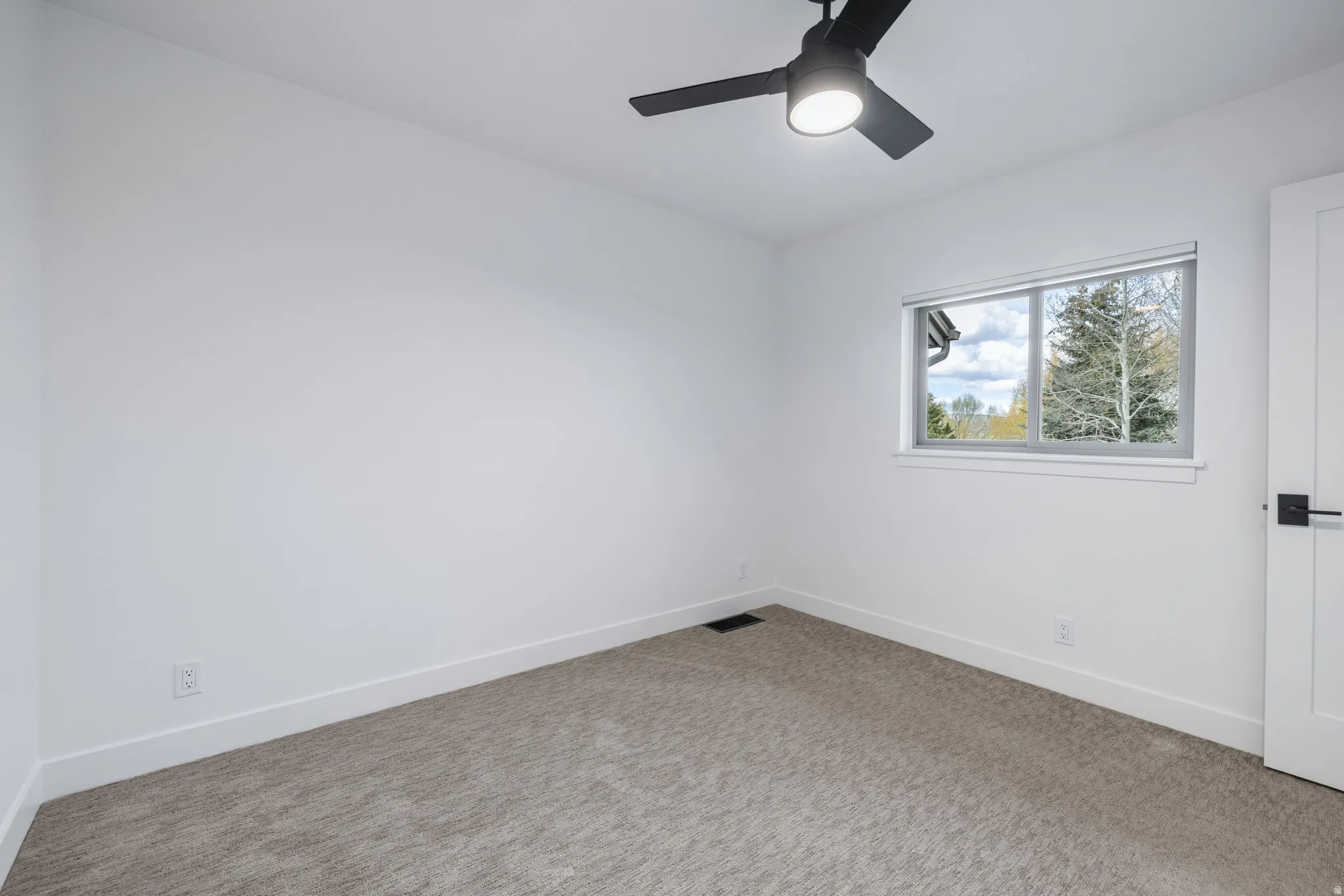Carpeted spare room with baseboards and a ceiling fan