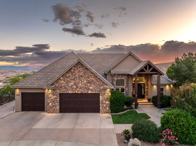 View of front facade with a garage, stucco siding, concrete driveway, and stone siding
