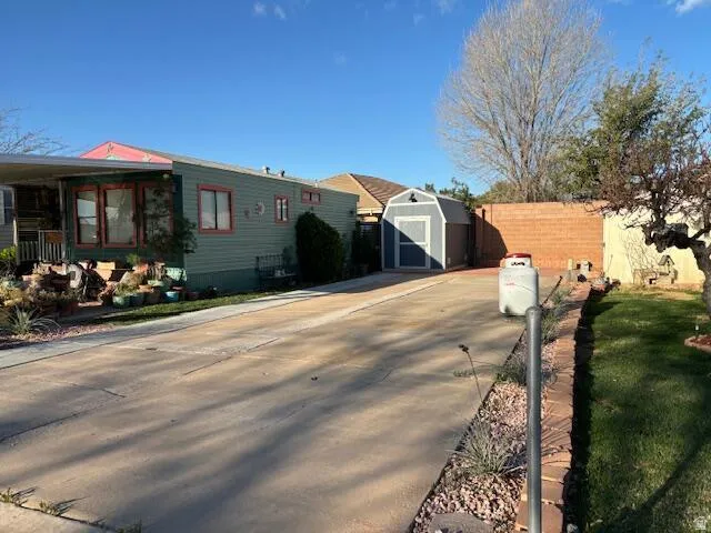 View of front of property with a storage shed, driveway, and a porch