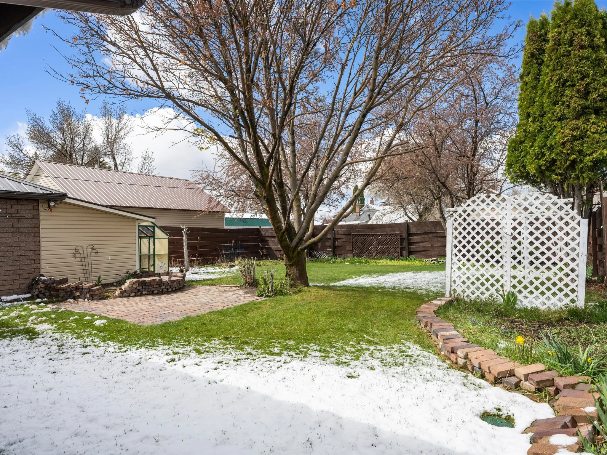 Yard layered in snow with a fenced backyard and a patio area