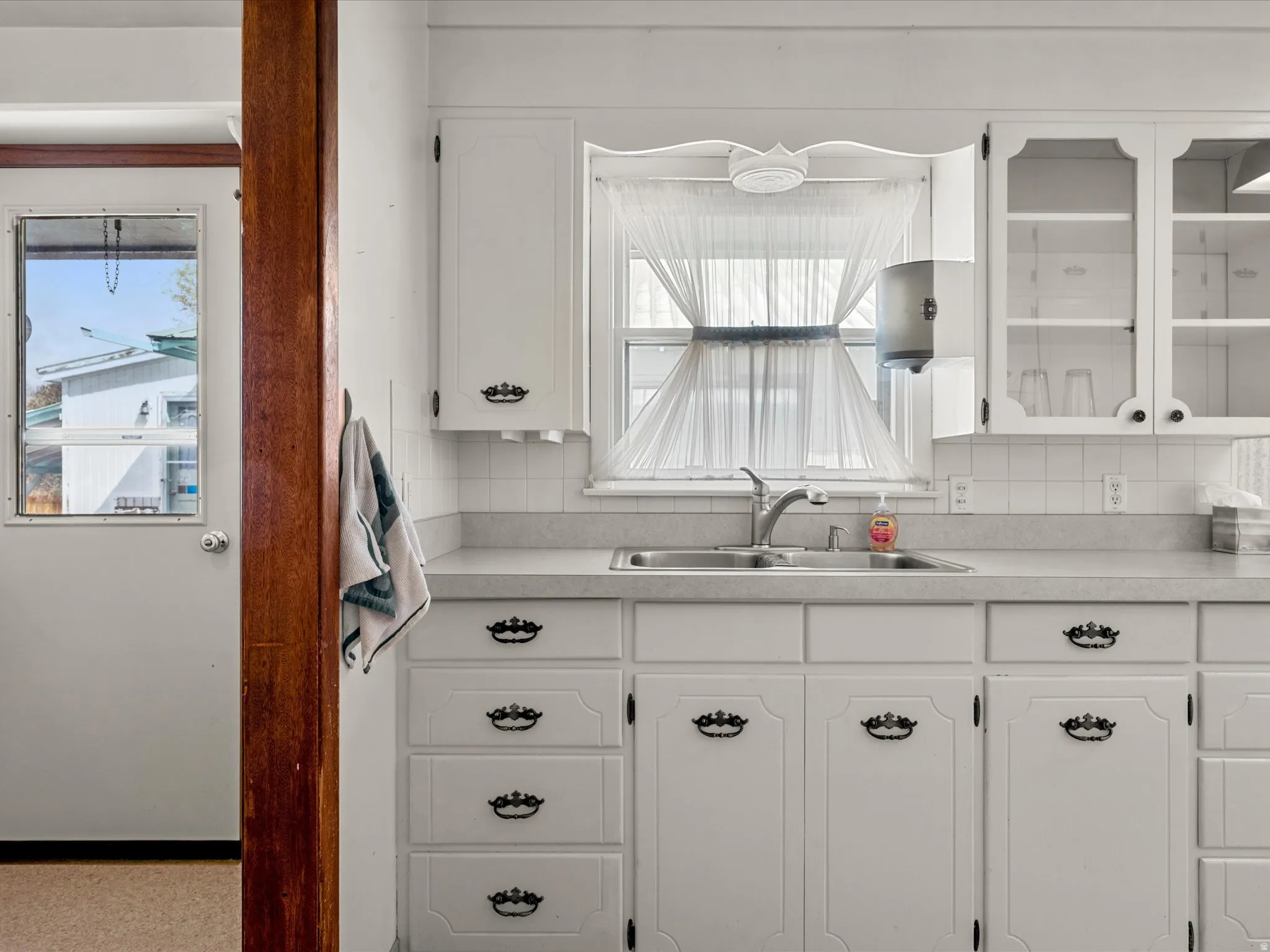 Kitchen featuring white cabinetry, light countertops, decorative backsplash