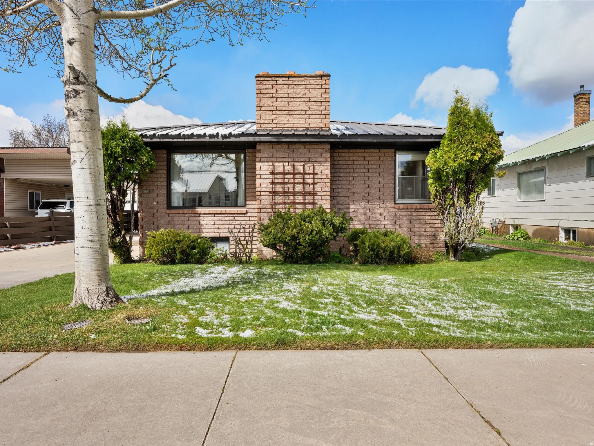 View of home's exterior featuring a metal roof, a yard, an attached carport, and a chimney