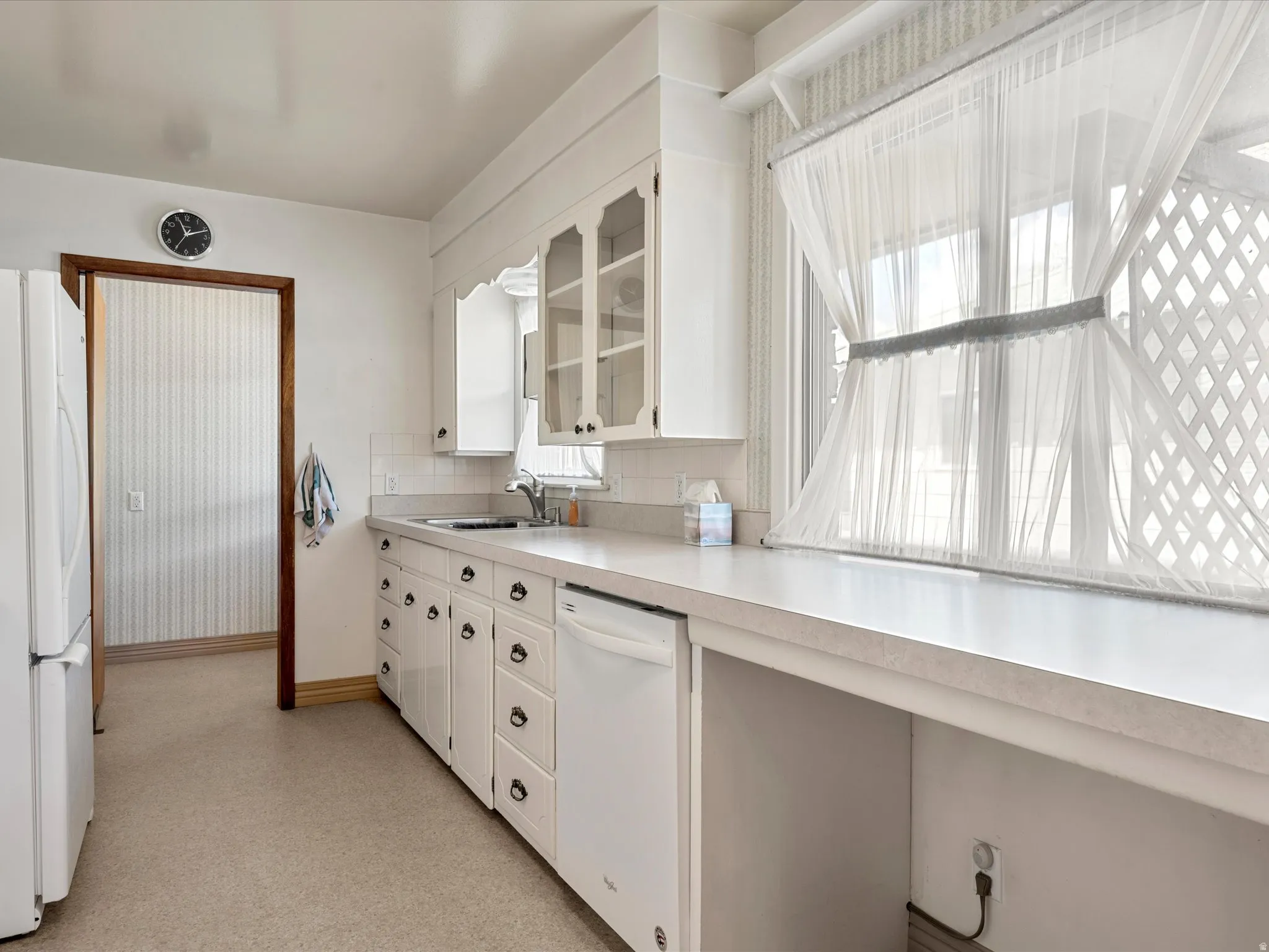 Kitchen featuring white cabinets, light countertops, white appliances, glass fronted cabinets, and decorative backsplash