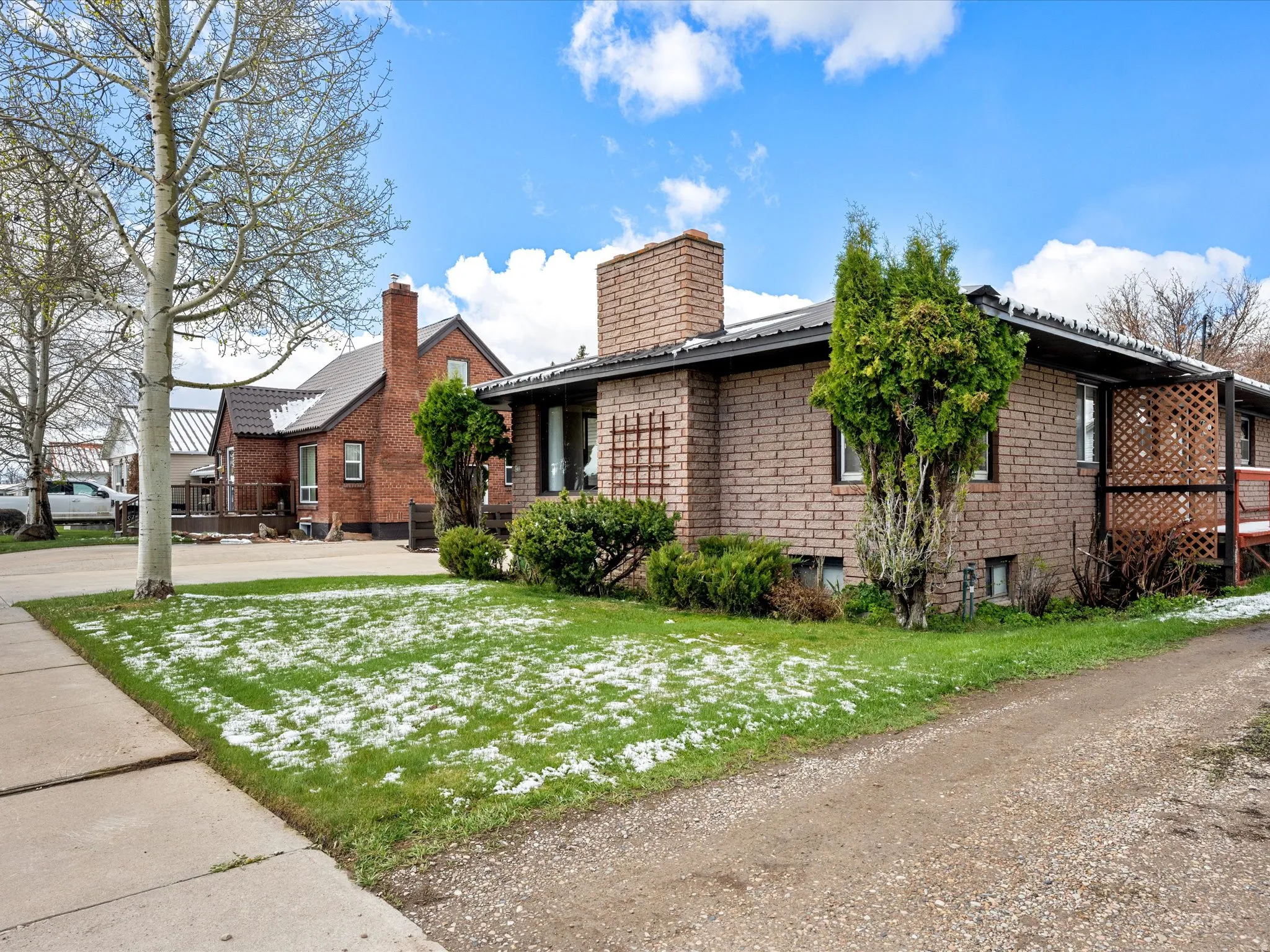 View of side of property with a lawn, a metal roof, and brick siding
