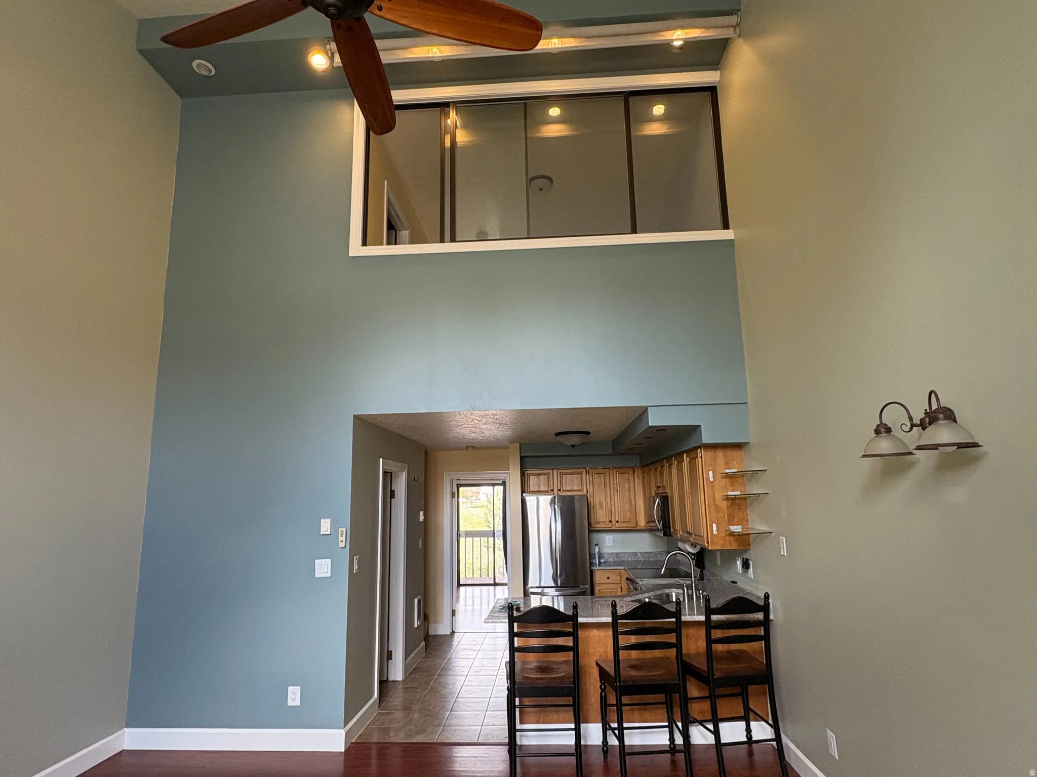 Open-concept living space featuring high ceilings, wood-finish flooring, and a ceiling fan
