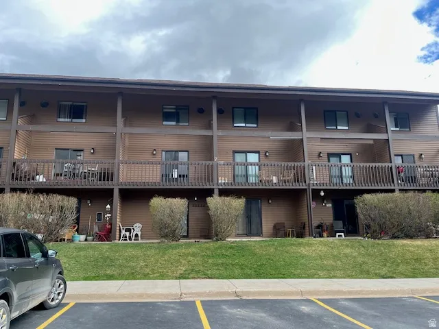 View of apartment building / complex featuring uncovered parking
