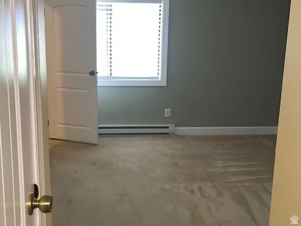 Empty room featuring ceiling fan, light colored carpet, a textured ceiling, and a baseboard heating unit