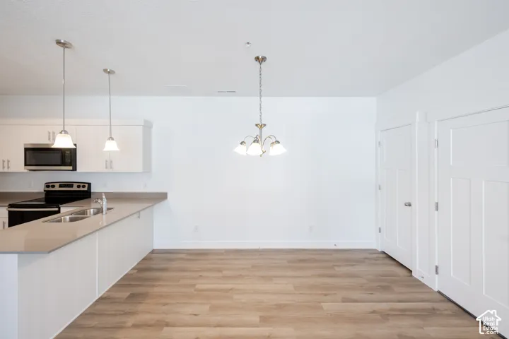 Contemporary kitchen with white cabinetry and stainless steel appliances, featuring a large island with an undermount sink