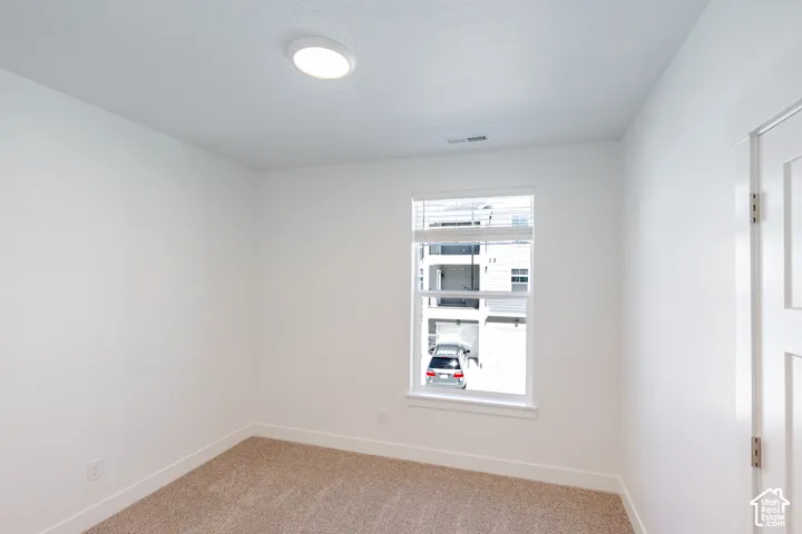 Recessed ceiling lighting, white walls, white window trim, white door, and textured carpet flooring