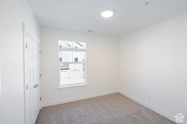 Neutral carpeted flooring, white walls, white trim, recessed lighting, and a single window