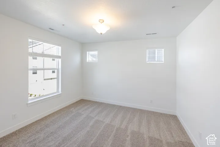 Carpeted room featuring multiple windows, white walls, and a ceiling-mounted light fixture
