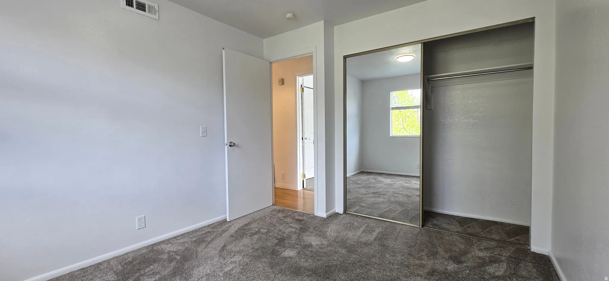 Unfurnished bedroom with dark carpet and a closet