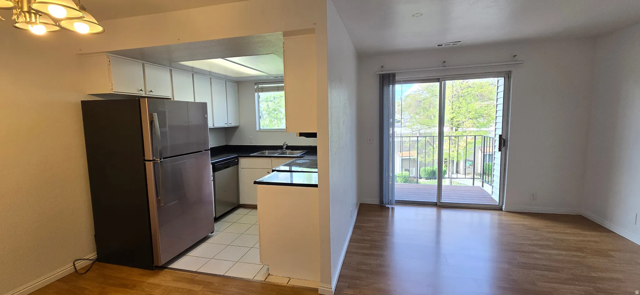 Kitchen featuring dark countertops, stainless steel appliances, light wood-type flooring, and white cabinets
