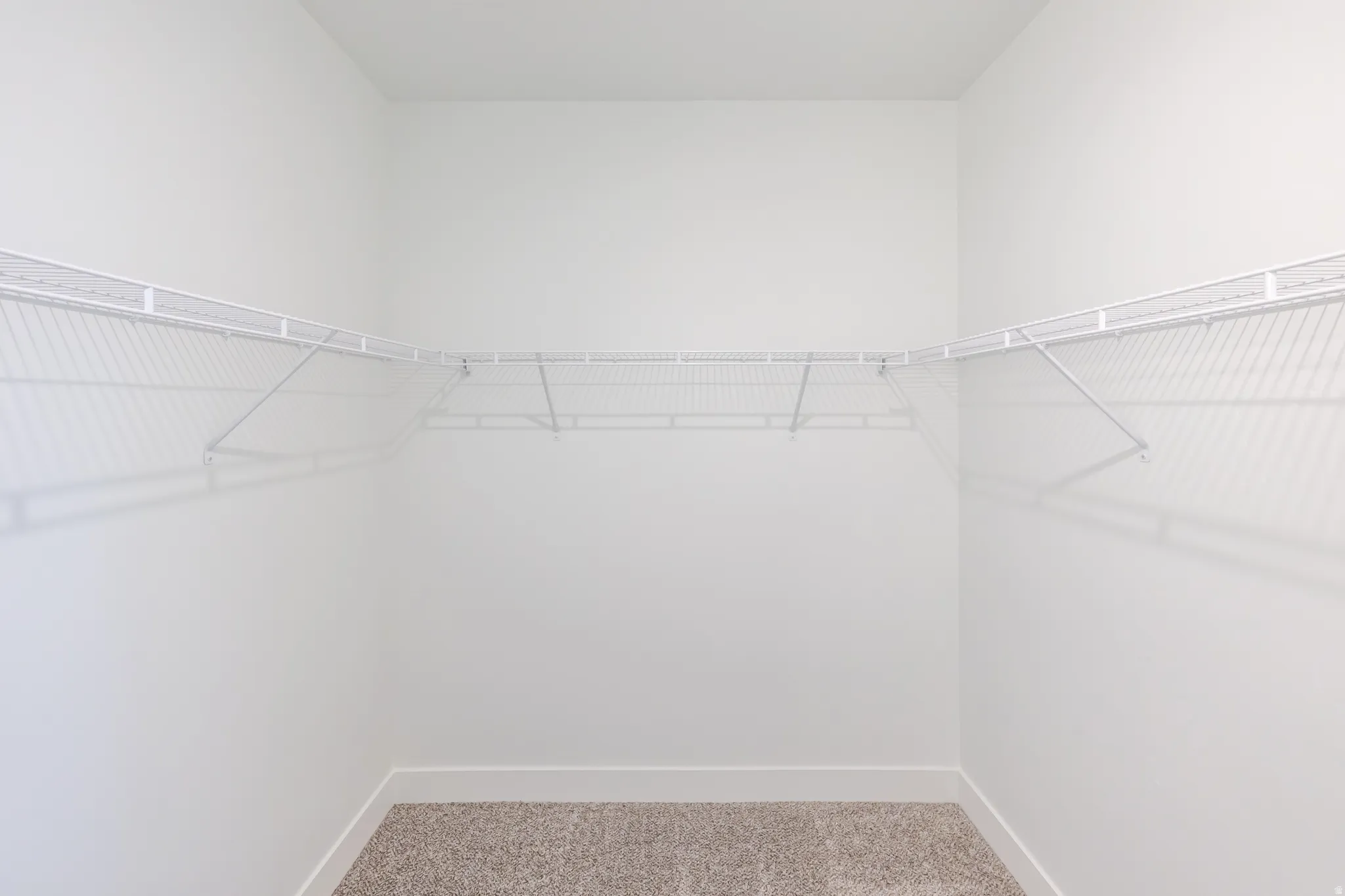 Corner closet with white wire shelving and neutral carpet