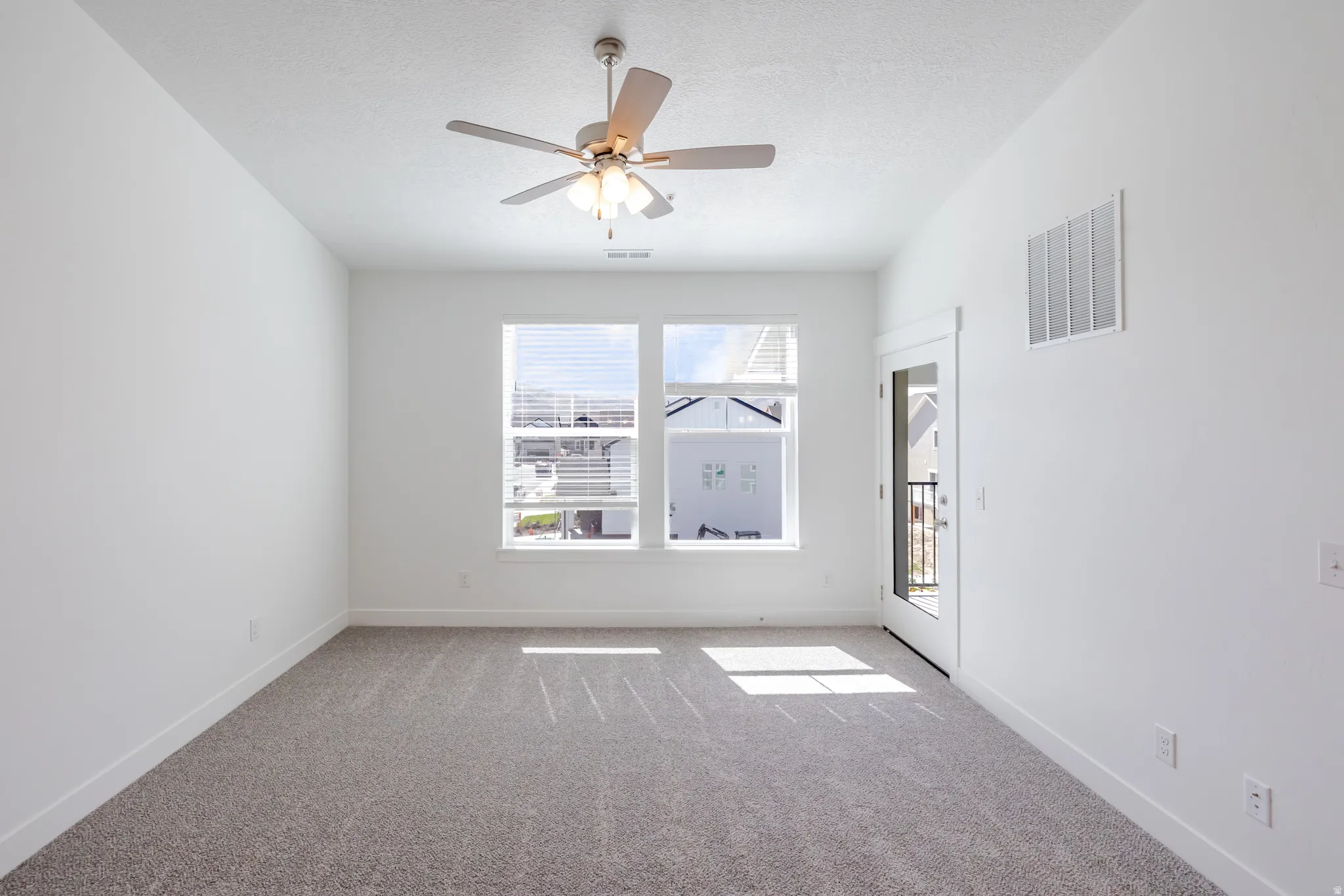 Bright room with neutral carpeting, white walls, and a ceiling fan with integrated lighting