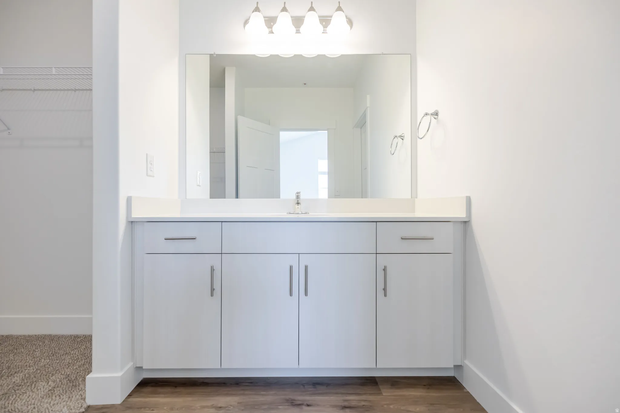 White vanity with an integrated sink, polished chrome faucet, and expansive mirror