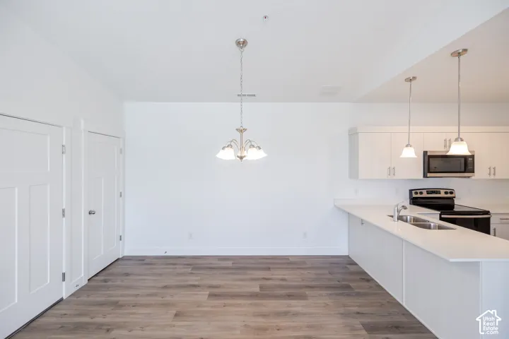 Kitchen featuring white cabinetry, stainless steel appliances, white countertops, and pendant lighting