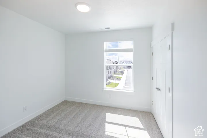 Neutral tone wall paint, flush mount ceiling lighting, carpet flooring, a window with horizontal blinds, and a built-in closet with double doors